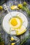 Honey in glass plate with dipper and fresh rapeseed flowers on rustic wooden background