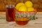Honey jar, dispenser, a bowl of honey, rosemary and a basket of lemons on wood with a honeycomb in the background