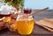 Honey in jar and honeycomb in small bowls. Teapot and cup of tea on the background.