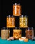 Honey with nuts, seeds, dried fruits. Still life photography. Honey packaged in transparent jars with lids in three rows on black