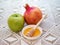 Honey in porcelain saucer, apple and pomegranate-still life for the Jewish New Year.