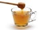 Honey pouring from wooden dipper into a cup