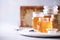 Honey products background. Honeycomb frame, bee pollen granules, honey in glass pot on grey concrete background. Copy space.