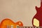 Honey sunburst electric guitar and back of mahogany guitar body on rough cardboard background, with plenty of copy space.
