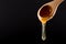 Honey in Wooden Spoon dripping isolated on black background