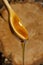 Honey on wooden spoon dripping from spoon. wooden background