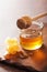 Honeycomb dipper and honey in jar on wooden background