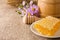 Honeycomb, flowers and honey in pot on sack