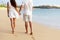 Honeymoon couple holding hands walking on beach