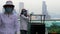 HONG KONG - APRIL 30, 2019: Cleaning Ladies with Masks Talk by Trash Can with Kowloon Behind 4k