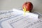 A honor roll recognition, certificate of achievement and high school diploma lies on table with small scroll and red apple.