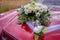 The hood of the car is decorated with a wedding flower with rings.