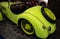 The hood of a green or yellow retro car. Lacquered, shiny antique vintage car. Close up