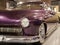 The hood, headlight and front wheel of the vintage car are purple. Chrome grille and bumper. Oldtimer in the garage.