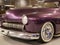 The hood, headlight and front wheel of the vintage car are purple. Chrome grille and bumper. Oldtimer in the garage.