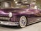 The hood, headlight and front wheel of the vintage car are purple. Chrome grille and bumper. Oldtimer in the garage.