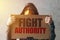 Hooded activist protestor holding Fight authority protest sign