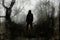 A hooded figure on a path through a spooky forest on a moody, foggy winters day