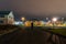 A hooded figure, silhouetted against a street light on an business estate at night