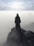 A hooded figure stands atop a cliff overlooking a sea of fog. Gothic art. AI generation