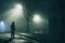 A hooded man standing underneath a street light. On a foggy winters night in the city