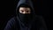 Hooded serious criminal in balaclava looking at camera, piercing glance, concept