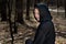 Hooded Woman in black robes deep in the Forest. Witches. Halloween and Gothic concept. Witchcraft and magic. Scary