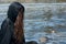 Hooded Woman with dark long hair in black robes in front of the Lake. Witches. Halloween and Gothic. Witchcraft and magic.