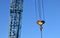 Hook gantry crane on the chain for lifting heavy loads on the background of a metal beam and a blue sky.