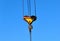 Hook gantry crane on the chain for lifting heavy loads on the background of a metal beam and a blue sky.