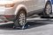 Hooked up car on a tow truck on a roadside, close up view of the rear wheel of a car and a transportation platform