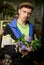 Hooligan male in peaked cap and tracksuit holding flower bouquet