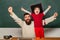 Hooray. Daddy and son raising clenched fists in hooray gesture. Father teaching her son in classroom at school. Yeah