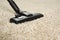 Hoovering beige carpet with modern vacuum cleaner, closeup. Space for text