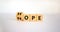 Hope or nope symbol. Male hand turns cubes and changes the word `nope` to `hope` on a beautiful white background. Business and