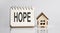 HOPE words written in an office notebook with wooden house. Financial Business concept