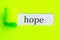 Hope is written on the surface from under torn light green paper