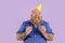 Hopeful male person with overweight in party hat holds fists on purple background