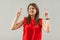 Hopeful and nervous. Portrait of worry brunette young woman in red shirt standing, clenching teeth, crossed fingers and hope to be