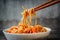 Hopsticks take noodles udon in sweet and sour sauce from plate. Traditional Asian cuisine