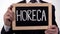 HoReCa written on blackboard in businessman hands, catering service industry