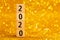 Horisontal numbers of 2020 on golden sparkling background.