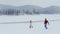 Horizontal back view of the joyful loving couple running along the beautifully covered meadow with fluffy snow in the