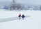 The horizontal back view of two lovers holding hands while walking along the snowy countryside. Christmas atmosphere.