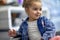 Horizontal close up portrait shot of beautiful child girl posing in fashionable clothes, feeling cute, sitting indoors in the home