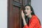 Horizontal close-up portrait of a woman in a red suit eavesdropping, spying on the door of the boss