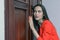 Horizontal close-up portrait of a woman in a red suit eavesdropping, spying on the door of the boss