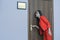 Horizontal close-up portrait of a woman in a red suit eavesdropping, spying on the door of the boss