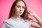 Horizontal closeup portrait of a young ginger girl with natural beauty. clean skin, long eyelashes over pink background