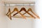 Horizontal detail view of an empty metal coatrack in a white wardrobe with four empty wooden coathangers